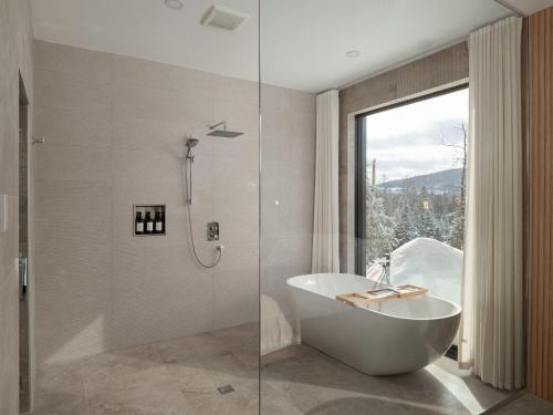 a bathroom with a tub and a shower with a window at Chalet Symbiose21 - Vue montagne, Sauna et spa in Saint Come