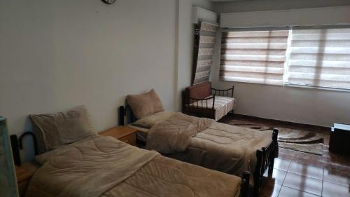 a bedroom with two beds and a chair and a window at بيت الحجر 2 in Amman