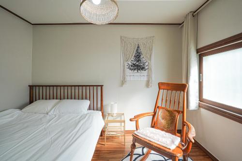 a bedroom with a bed and a chair and a window at Traditional Korean houses Stay Yeon in Busan