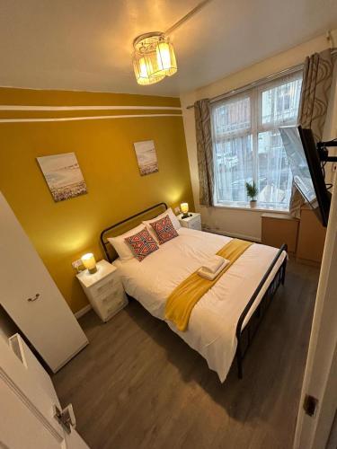 a bedroom with a bed with a yellow wall at West Bromwich Apartment for 2 guests in West Bromwich