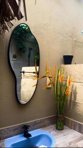 a bathroom mirror with a sink and a vase with flowers at Cabaña la Industrial in Coveñas