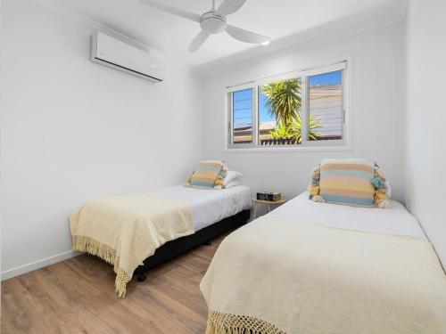 two beds in a room with a palm tree at The Eddy Escape in Kingscliff