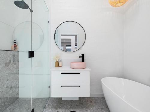 a bathroom with a white tub and a mirror at The Eddy Escape in Kingscliff