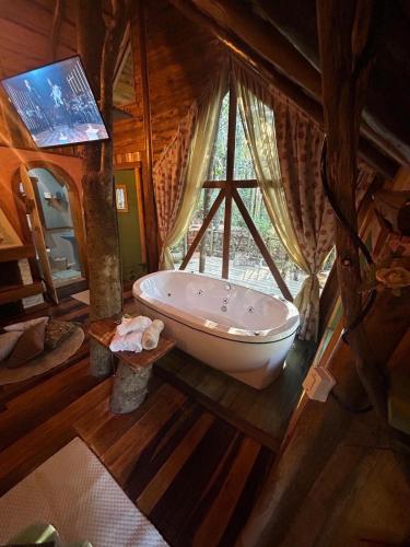 a bathroom with a large window and a bath tub at Casa na Árvore in Rio dos Bugres
