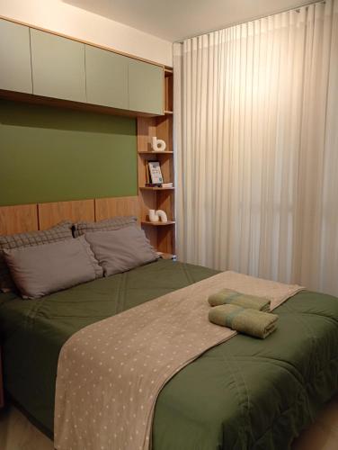 a bedroom with a green bed with two pillows on it at Studio Centro Curitiba in Curitiba