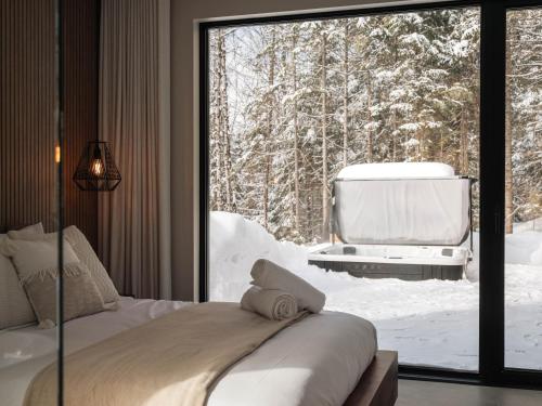 a bedroom with a bed and a large glass window at Chalet Symbiose21 - Vue montagne, Sauna et spa in Saint Come