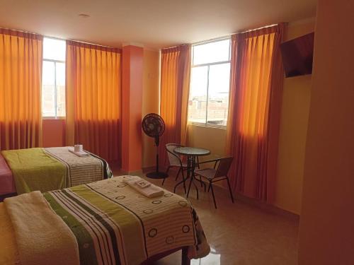 a room with two beds and a table and a window at Hostal Mitopampa in Lambayeque