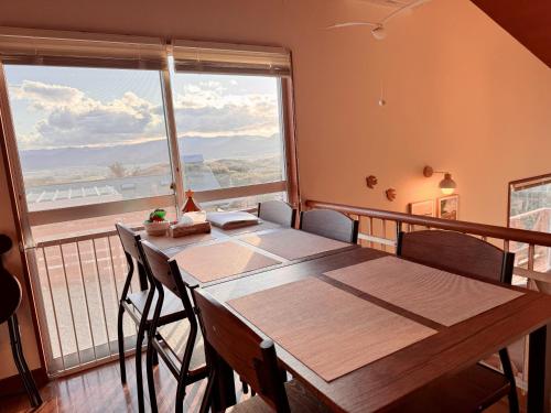 a table and chairs in a room with a large window at 羽咲亭乃台 in Kannami