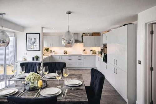 a kitchen with a table and chairs and a kitchen with white cabinets at The Grand 4-Bed Ebbsfleet Home - Big Garden & Parking, Near Bluewater in Greenhithe
