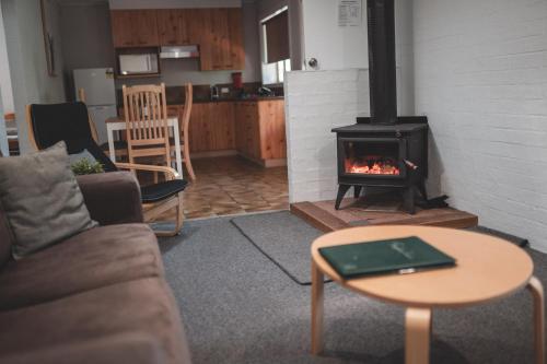 a living room with a fireplace and a couch at Kianinny Bush Cottages in Tathra
