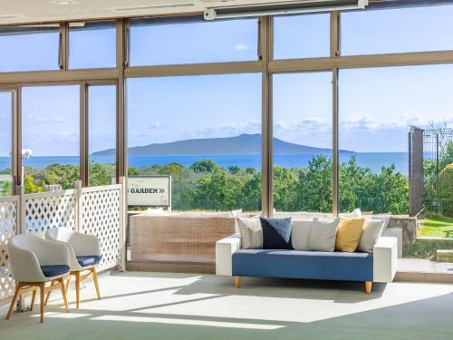 a living room with a couch and chairs and windows at Wan Wan Paradise Premier Izukogen in Ito