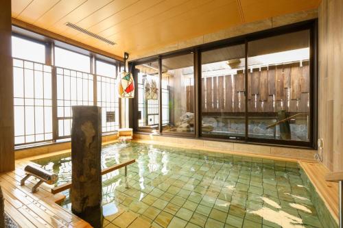 a pool in a room with a large window and a swimming pool at Natural Hot Spring Echizen no Yu Onyado Nono Fukui in Fukui