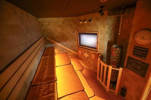 a room with a bench in a room with a tv at Natural Hot Spring Echizen no Yu Onyado Nono Fukui in Fukui