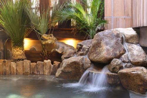 a fish pond with a waterfall and a giraffe standing next to a waterfall at Natural Hot Spring Echizen no Yu Onyado Nono Fukui in Fukui