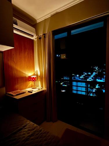 a bedroom with a view of a city at night at Apê Moderno in Caxambu
