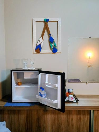 an open refrigerator sitting on a wooden table with glasses at Quarto em residência familiar in Navegantes