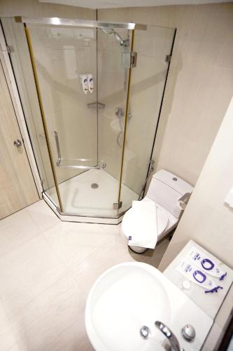a bathroom with a shower and a toilet and a sink at FOX Hotel Gorontalo in Gorontalo