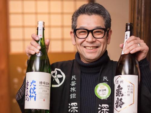 a man holding up two bottles of wine at Fukashiso in Matsumoto
