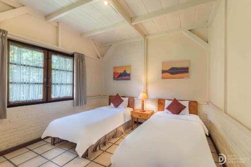 two beds in a room with two windows at Hotel Grand Panorama Lembang in Lembang
