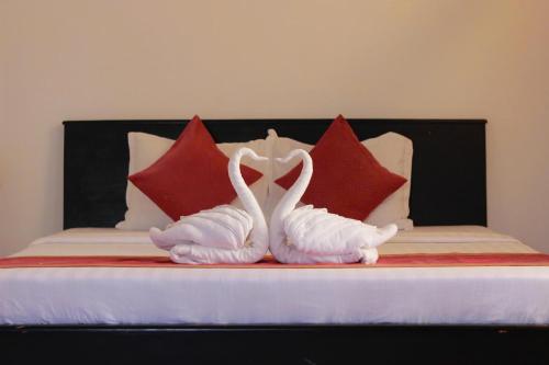 two white swans sitting on a bed with red pillows at Matie Beach Hotel & Resort in Kao Kuil