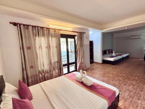 a hotel room with a bed with shoes on it at Matie Beach Hotel & Resort in Kao Kuil