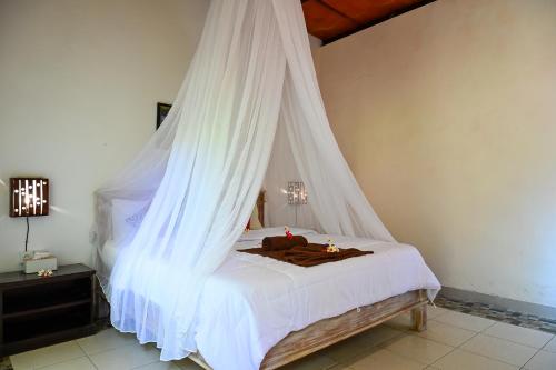 a bedroom with a bed with a mosquito net at Kubu Pertiwi Pemuteran in Pemuteran