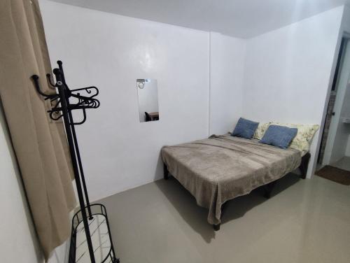 a small white room with a bed with blue pillows at Lorna's Home in Panglao Island