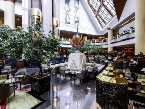 a lobby with tables and chairs in a building at The Heritage Grand Khon Kaen Hotel and Convention in Khon Kaen