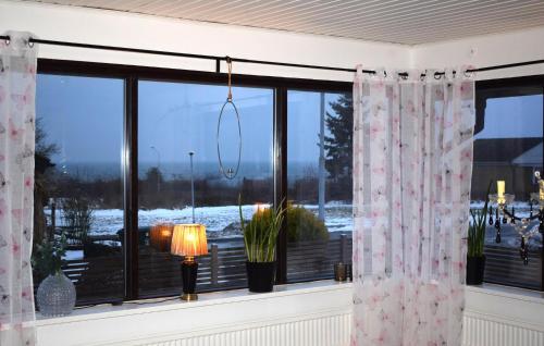a window with curtains and a lamp in a room at Beautiful Home In Simrishamn in Simrishamn