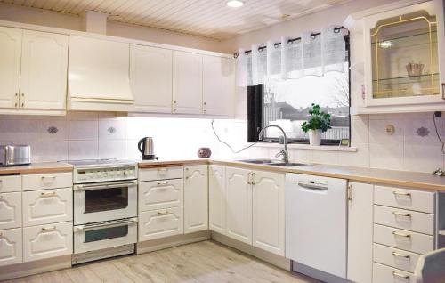 a kitchen with white cabinets and a sink and a window at Beautiful Home In Simrishamn in Simrishamn