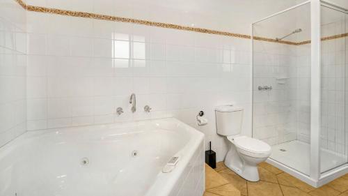 a white bathroom with a tub and a toilet at Cowes Beachfront Penthouse in Cowes