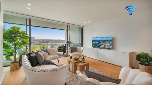 a living room with white furniture and a large window at Marina Belle in Shellharbour