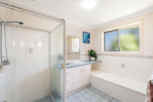 a bathroom with a shower and a tub and a sink at Waratah Retreat in Evans Head