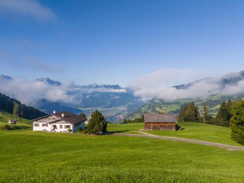 a house on a green hill with mountains in the background at Villa mit Seeblick in Amden