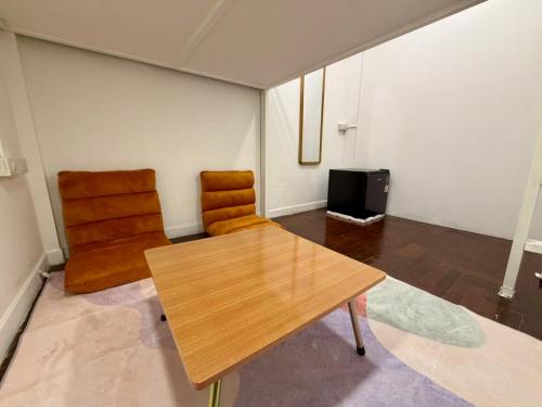 a living room with a wooden table and a chair at Comfy Crib Hostel 2 in Bangkok