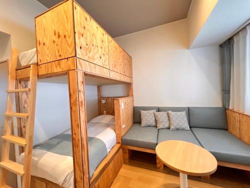 a bunk bed room with a couch and a table at Hotel Naturwald Furano in Furano