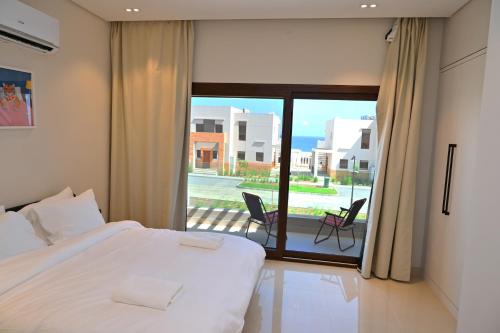 a bedroom with a bed and a view of a balcony at Wateera Jebel Sifah-Beachfront & Golf View in As Sīfah