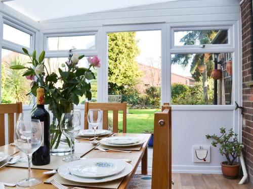 a table with plates and glasses and a vase with flowers at Pam's Plaice in Offord Cluny