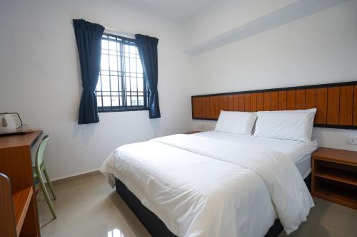 a bedroom with a large white bed and a window at TEBRAU 11 Guesthouse in Johor Bahru