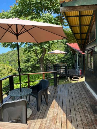 a wooden deck with a table and chairs and an umbrella at Amapondo in Port St. Johns