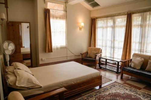 a bedroom with a bed and a chair and a mirror at Meizies Home in Shillong