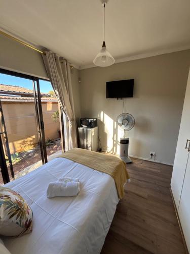 a bedroom with a large white bed with a large window at Amru Guesthouse B&B in Brackenfell