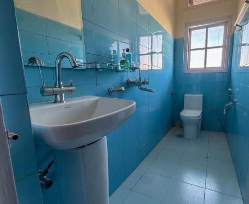 a blue bathroom with a sink and a toilet at Meizies Home in Shillong