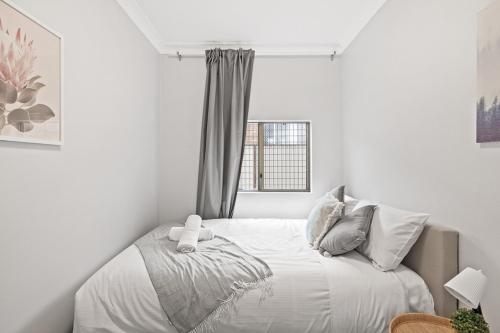 a white bedroom with a bed with a window at Signature Double Room in Auburn - Shared Bathroom in Sydney
