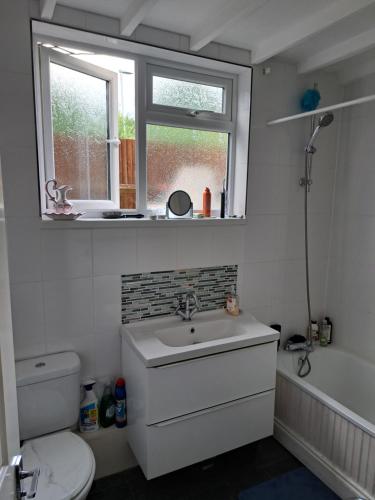 a bathroom with a sink and a toilet and a window at The Old Chip Shop in Ilchester
