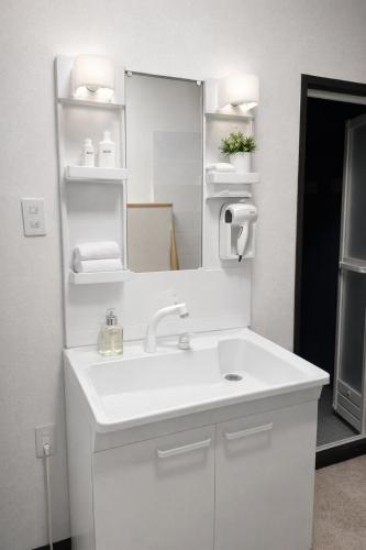 a white bathroom with a sink and a mirror at Local LifeYOMITAN in Yomitan