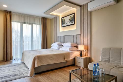 a bedroom with a bed and a couch and a table at Hotel Villa Ekaterina in Vakarel