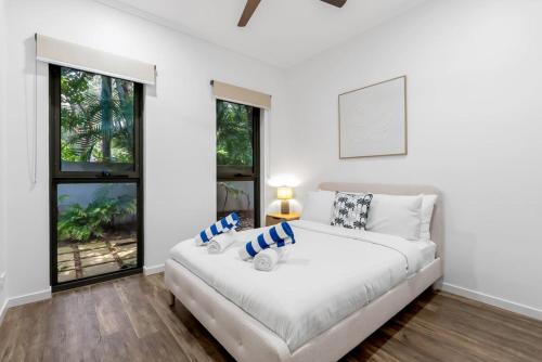 a white bedroom with a large bed and windows at Belle Escapes Samaya in Palm Cove