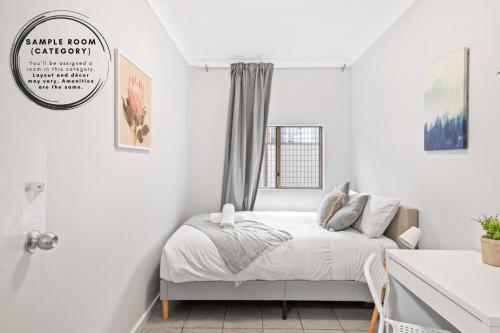 a white bedroom with a bed and a window at Signature Double Room in Auburn - Shared Bathroom in Sydney