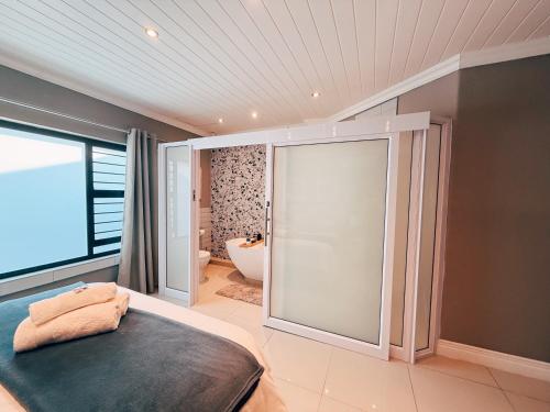 a bedroom with a large glass door leading to a bathroom at Lemon & Blue Guest House in Welkom